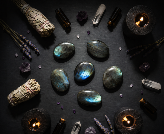 Pierre plate en labradorite de Madagascar, pierre naturelle de protection et d’intuition, présentée dans une ambiance ésotérique avec bougies et cristaux.